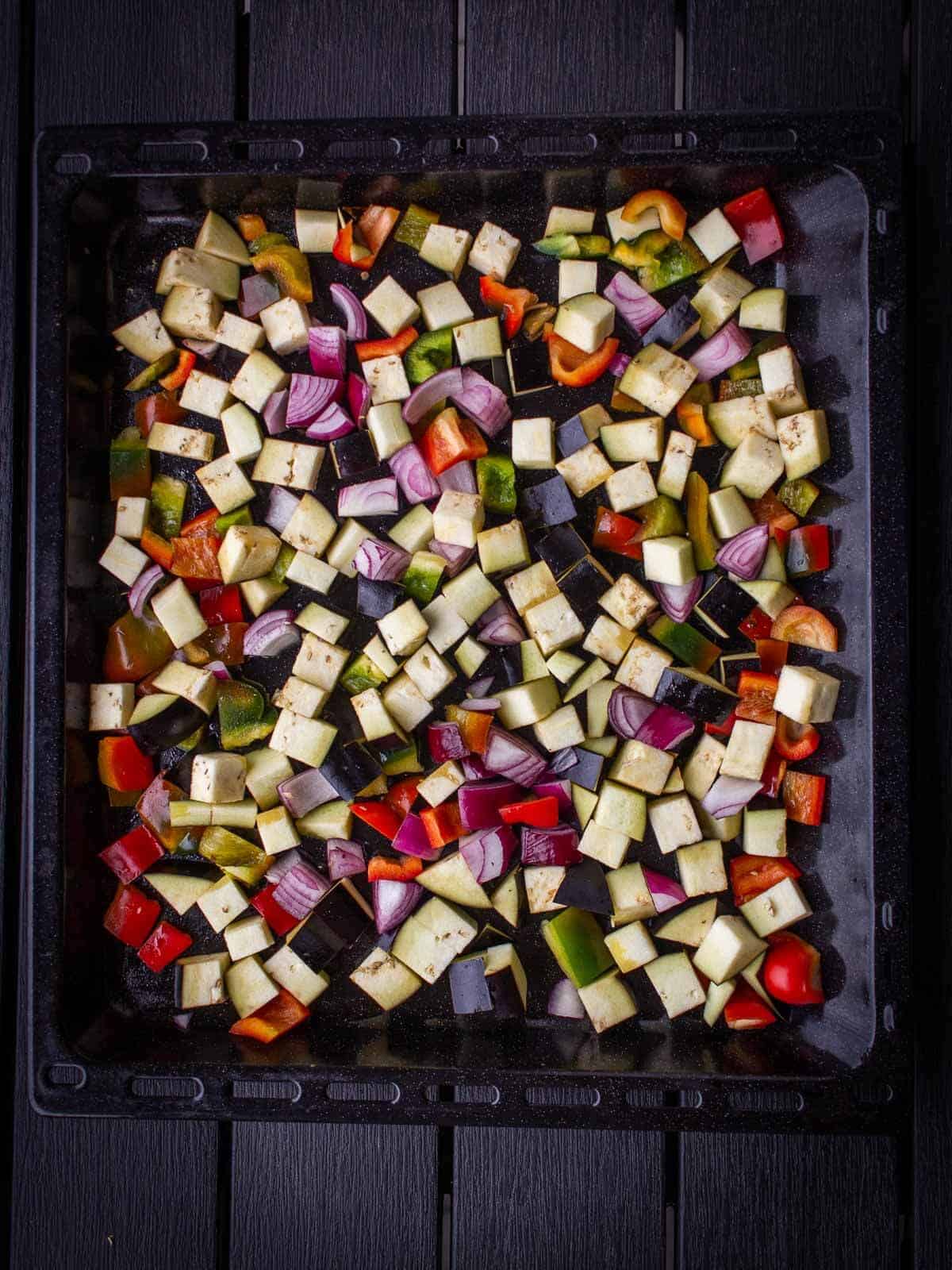 uncooked diced veggies on an baking tray with parchment paper.