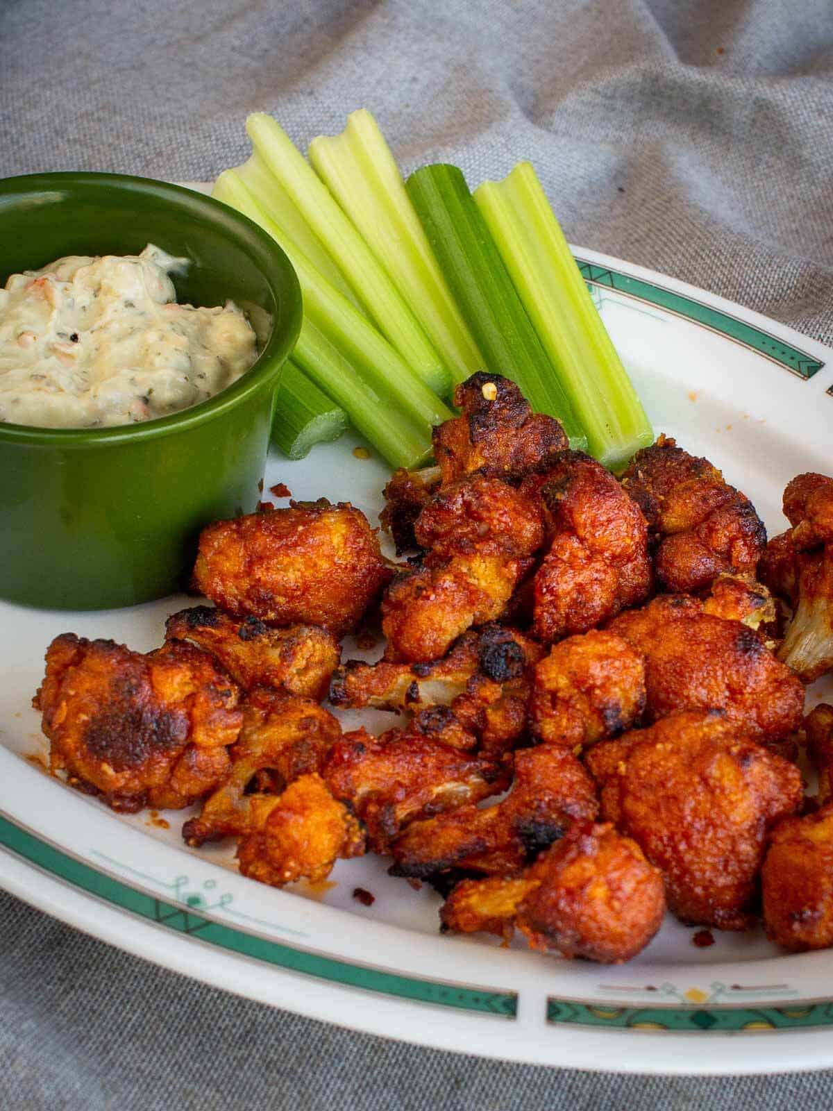 cauliflower wings served with vegan ranch sauce and celery sticks.