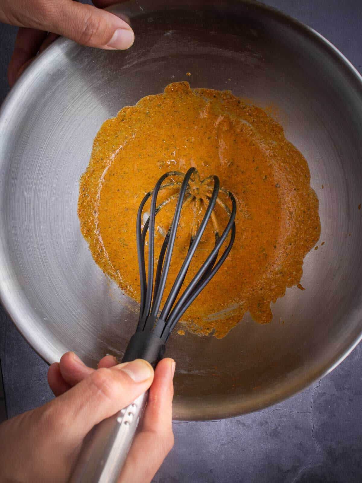 mixing dry and wet ingredients of tahini sauce in a mixing bowl.