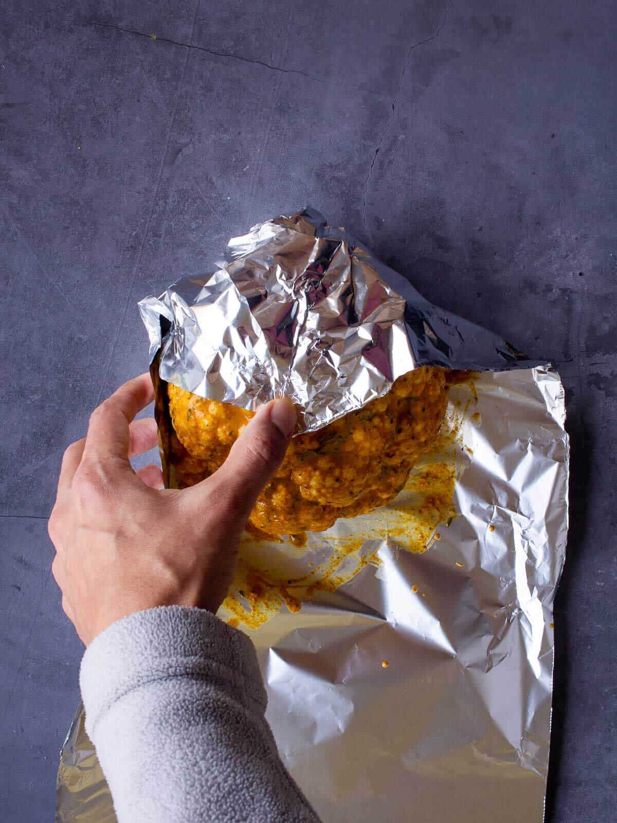 wrapping cauliflower head with aluminium foil.