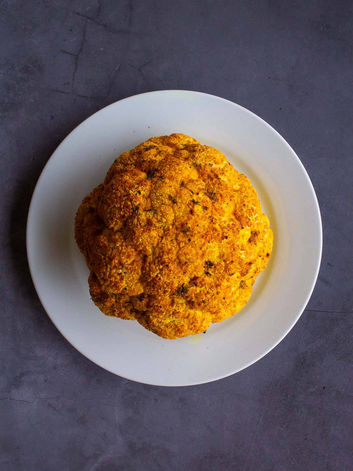 Spiced Roasted Cauliflower head served on a white plate.