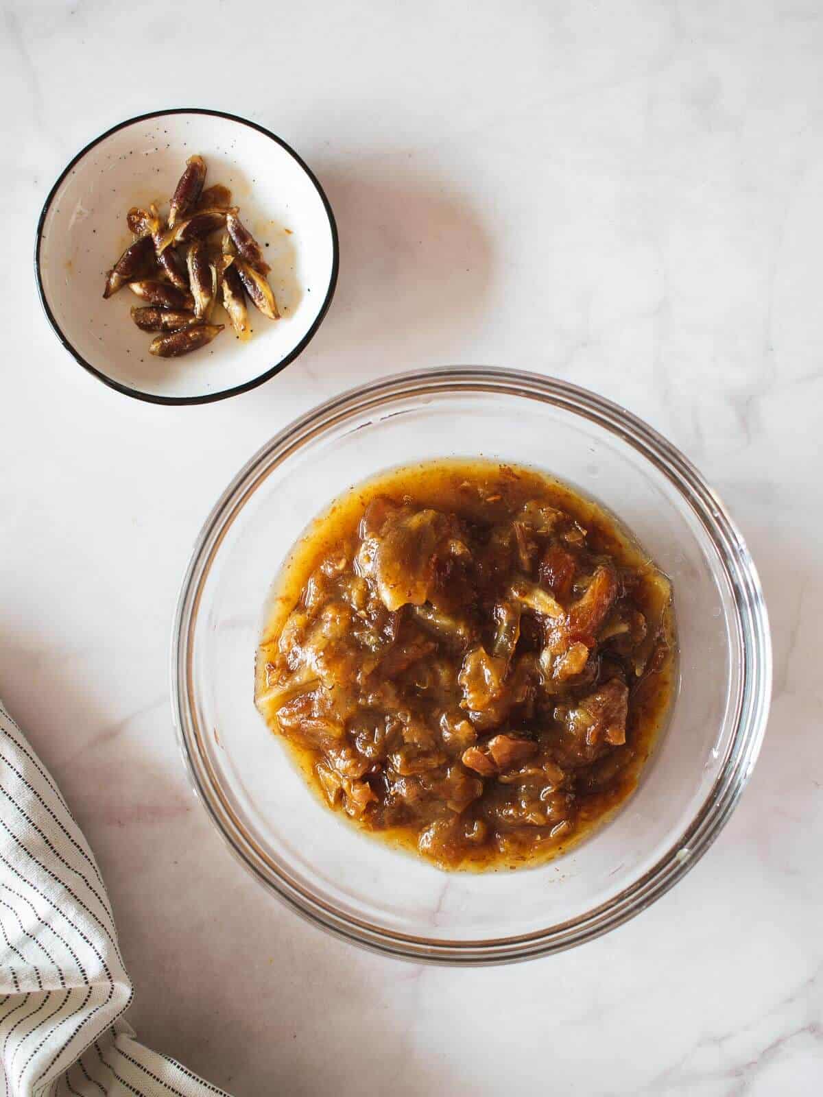 unblended dates flesh next to a mini bowl with date pits.