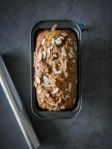 half-baked vegan banana bread loaf with added slivered almonds.