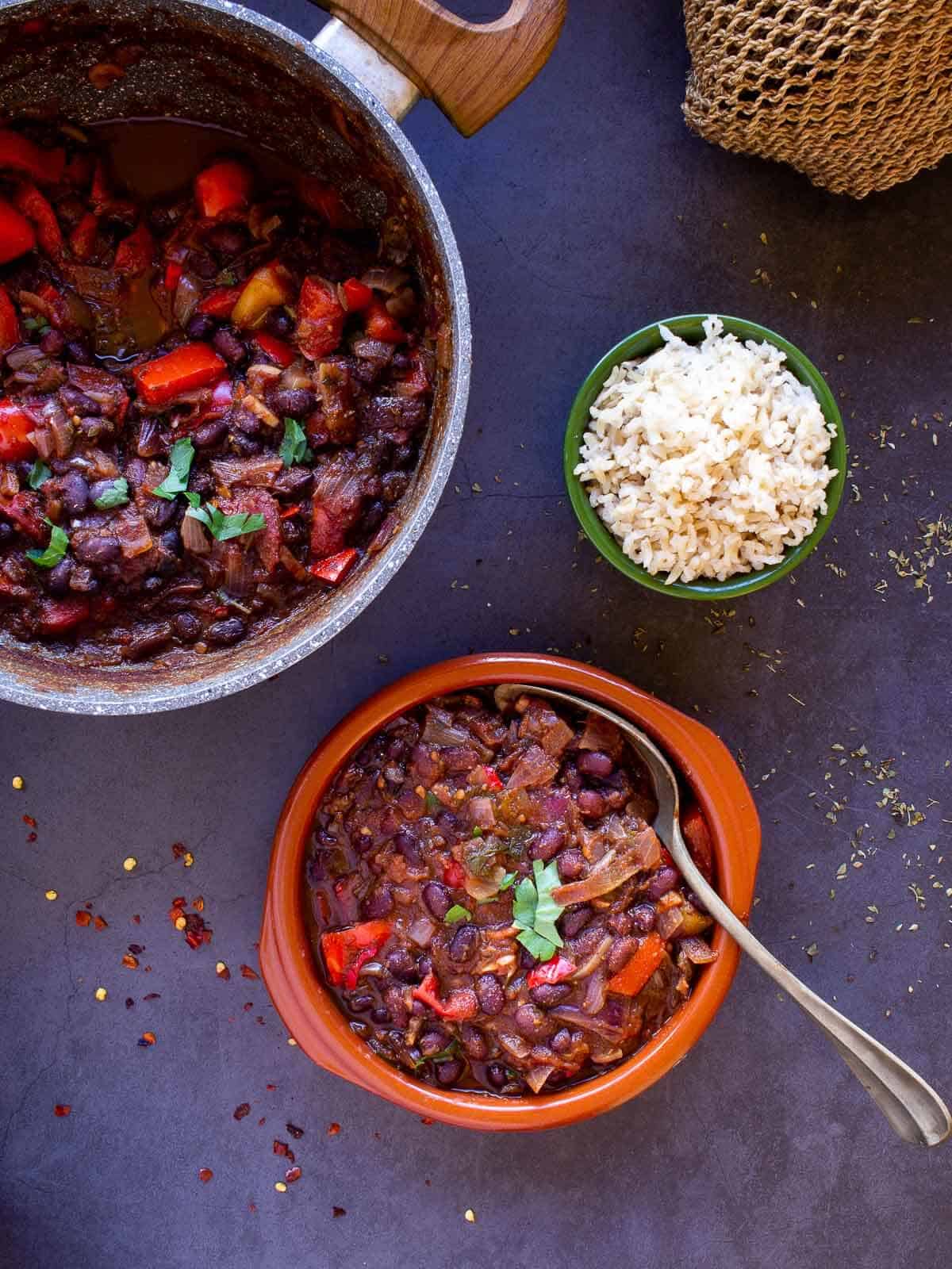 vegan bean chili sin carne served next to a big serving pot and brown rice.