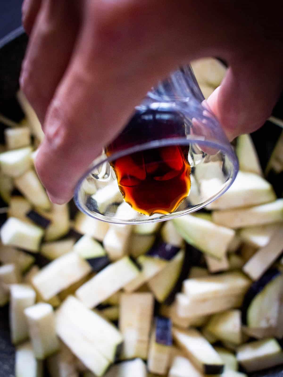 pouring soy sauce over eggplant cubes