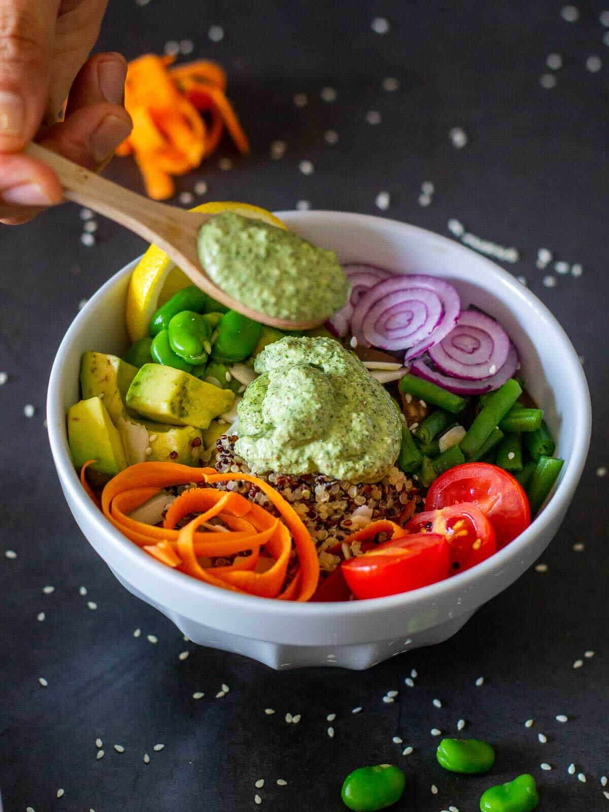 Pouring mint sauce on Vegan Poke Bowl for a vegan spring meal