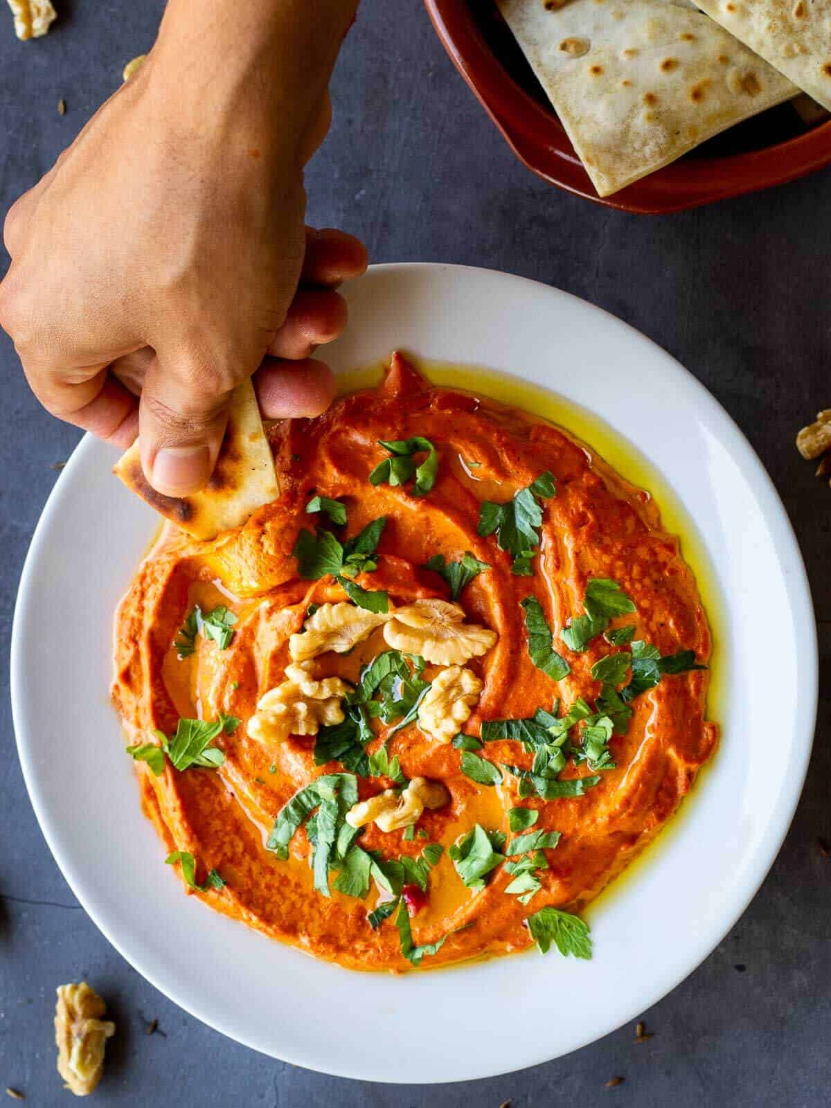 muhammara dip scooping with pita bread