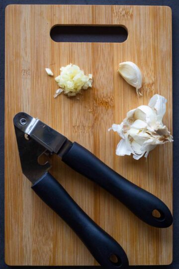 minced garlic in a wooden table with a garlic masher.