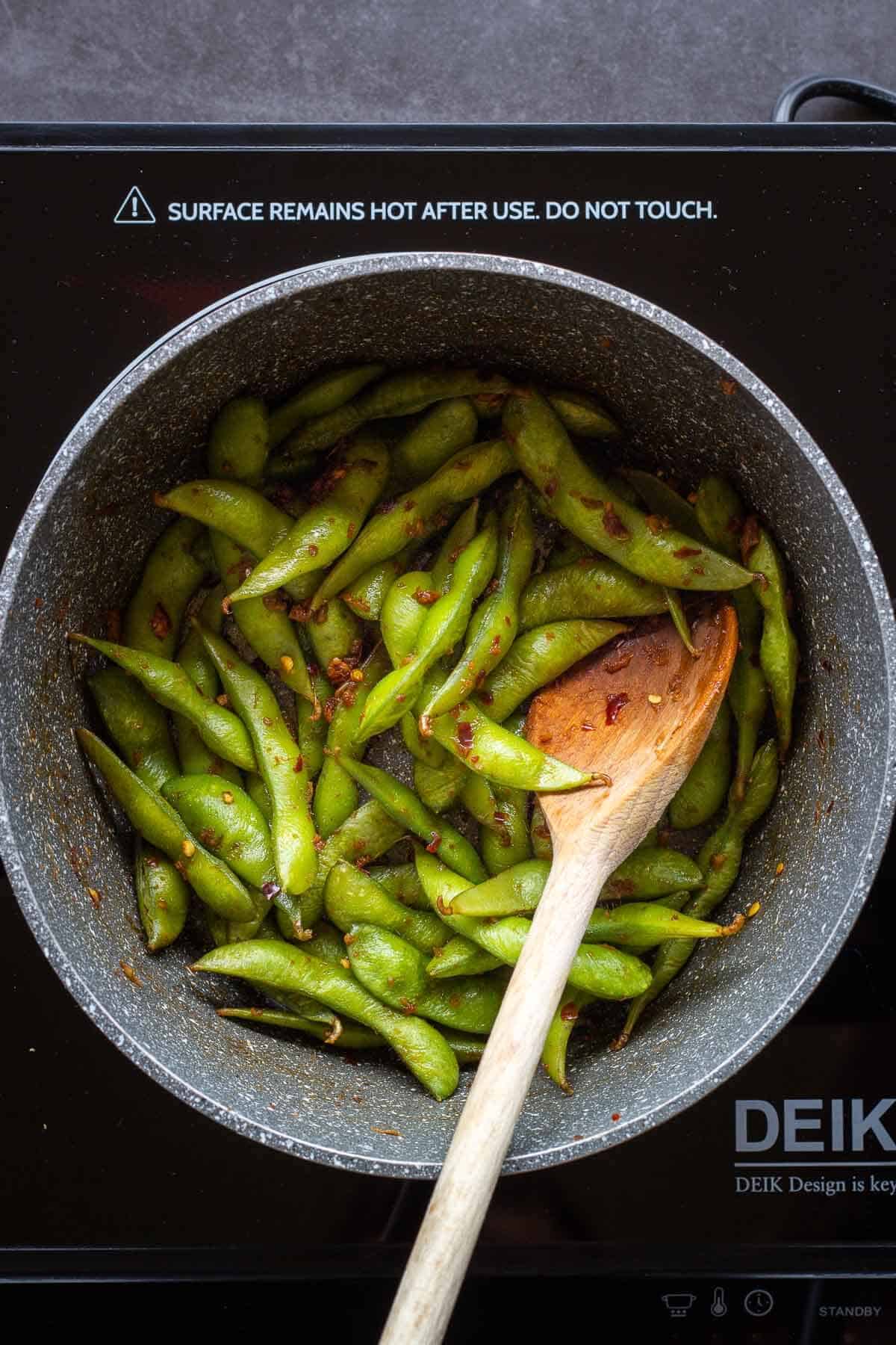 Stirring Garlic Edamame with Seasonings.