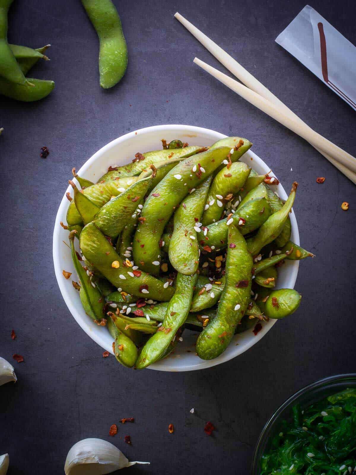 garlic edamame served with chopsticks.