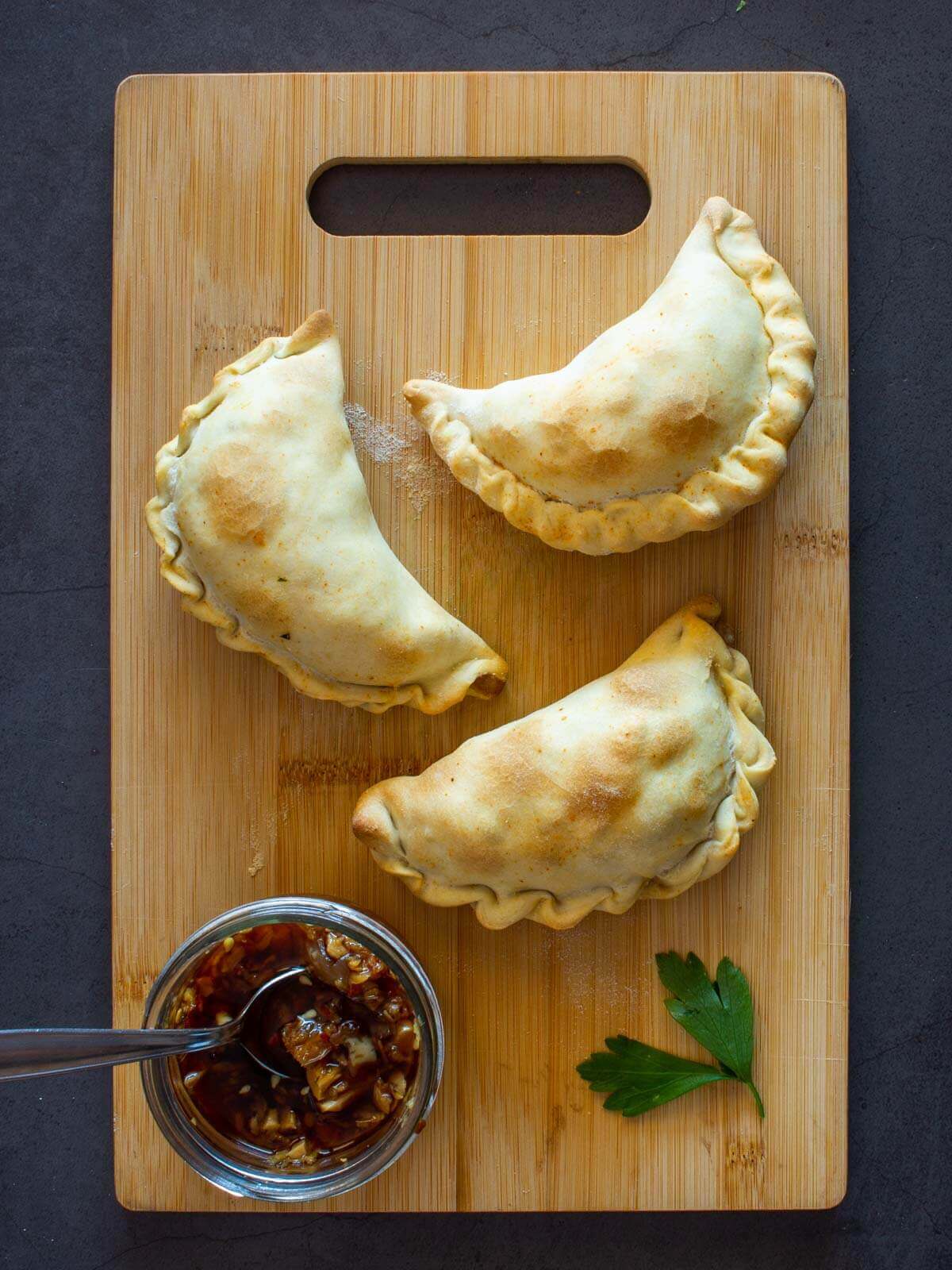 Mushroom empanadas served after baking with chimichurri sauce.