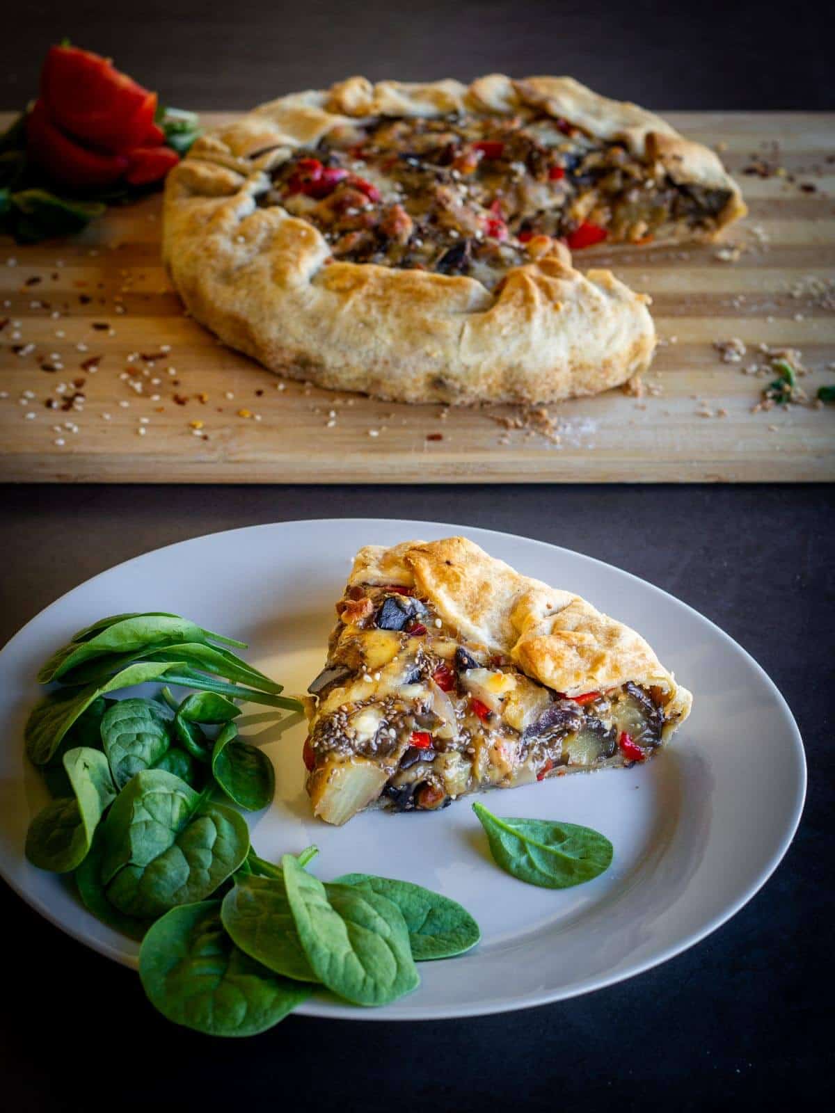 Vegan Eggplant Pie portion served with fresh spinach in a plate.