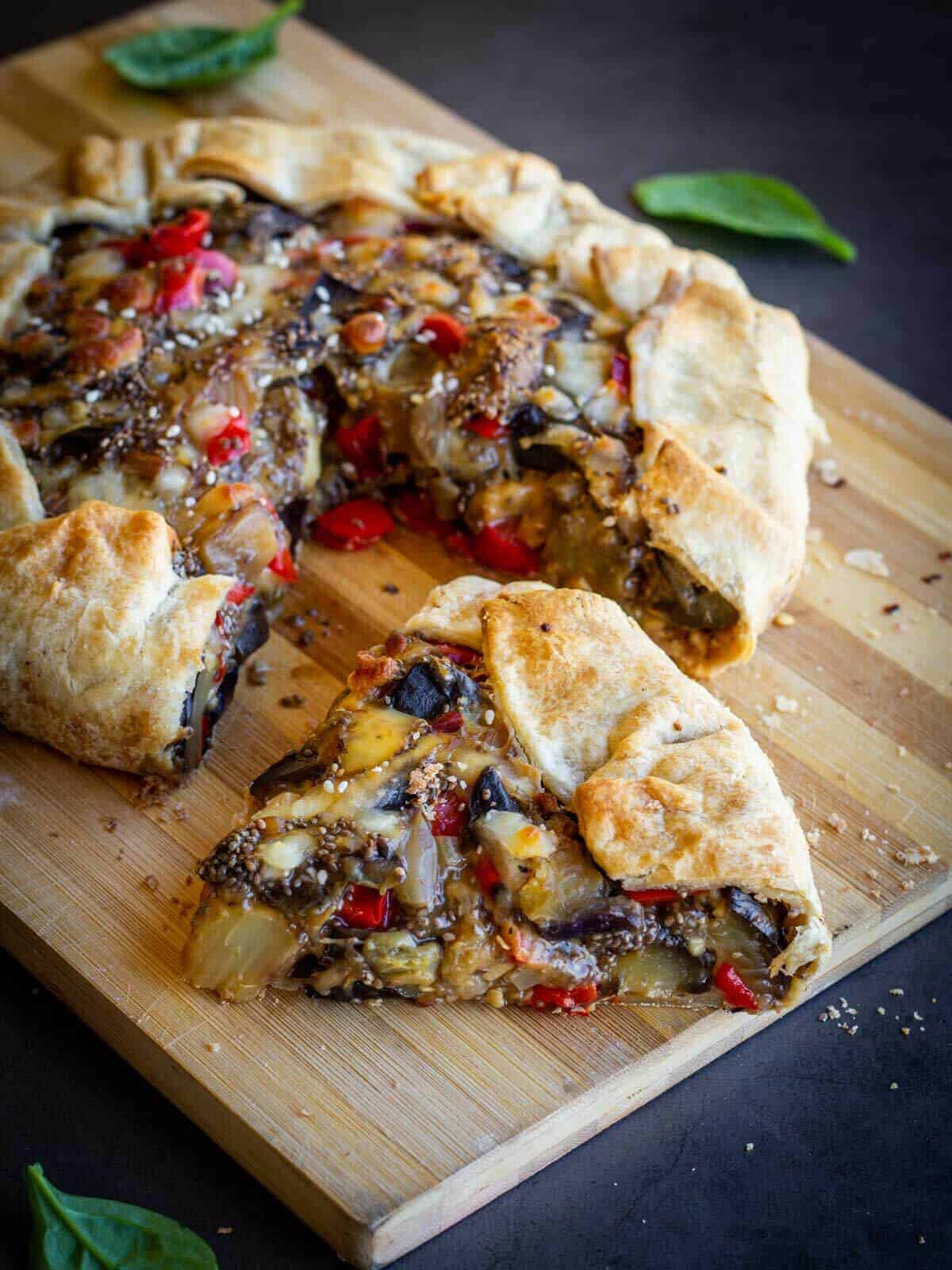 Vegan Eggplant Pie with Portion on a wooden cutting board.