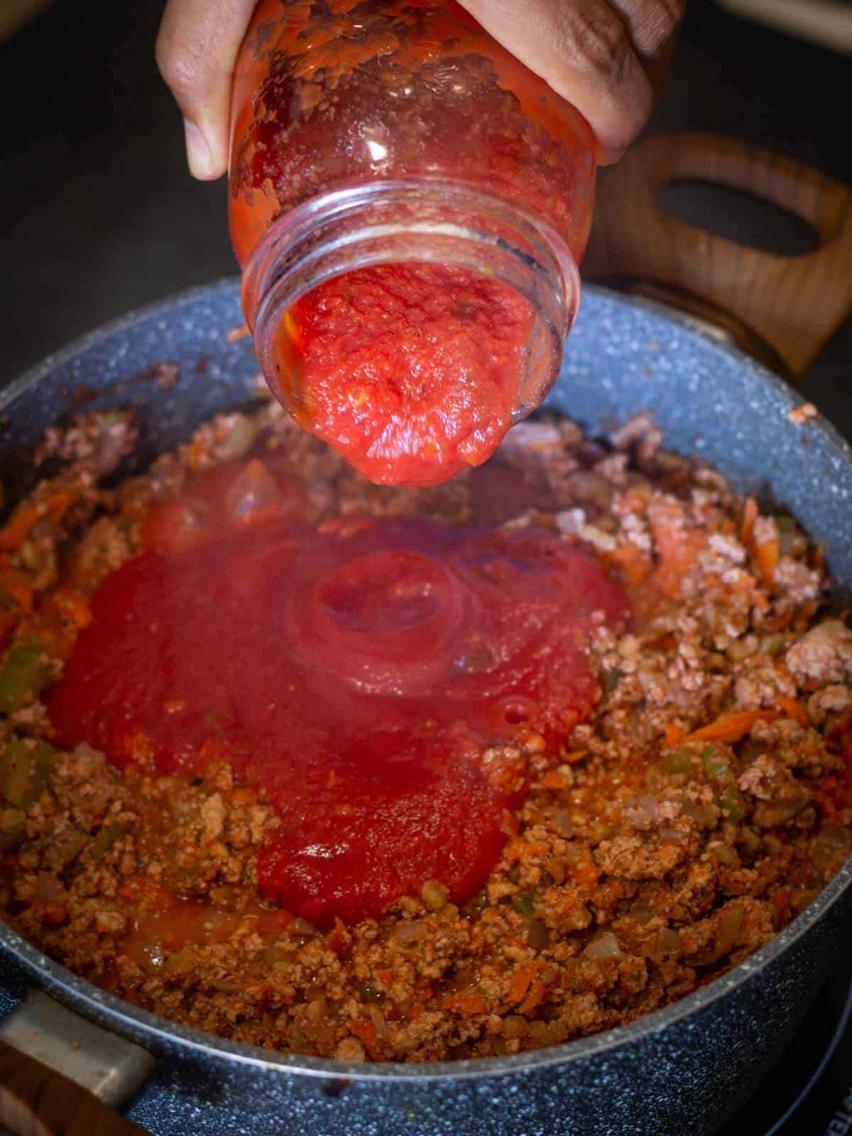 Vegetable Bolognese pouring tomato sauce.
