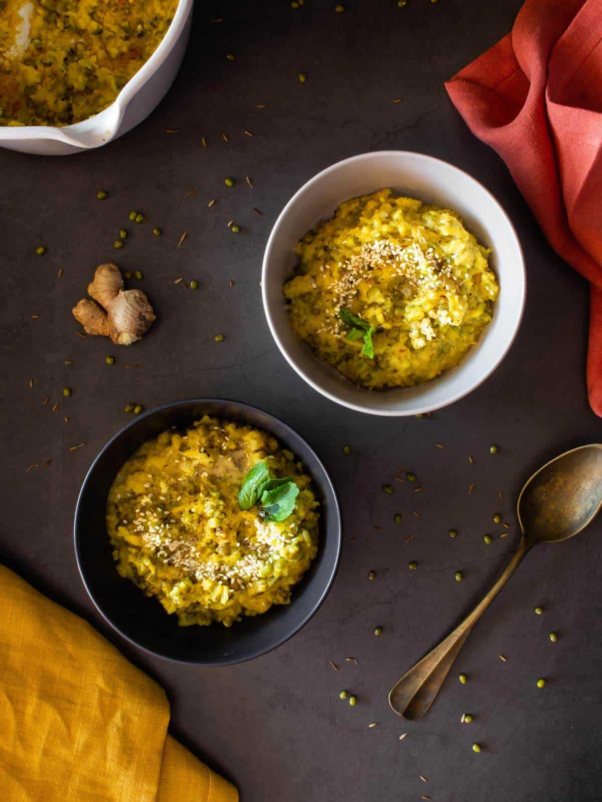 two bowls of kitchari and a ginger root in a table.