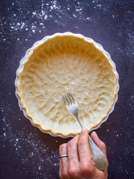 pinching dough in the bottom with fork of the vegan pastry.