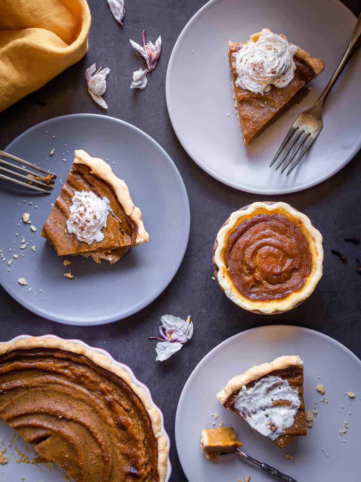 vegan pumpkin pie portions served on small plates and a small one-portion sized pie on its pan.