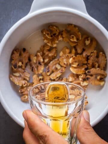 adding maple syrup to the saucepan with toasted walnuts.