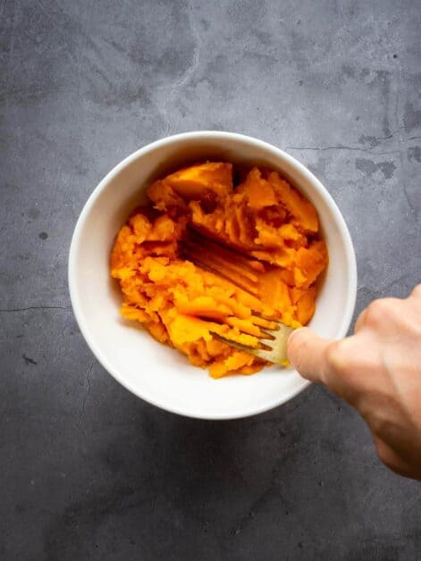mashing pumpkin in saucepan