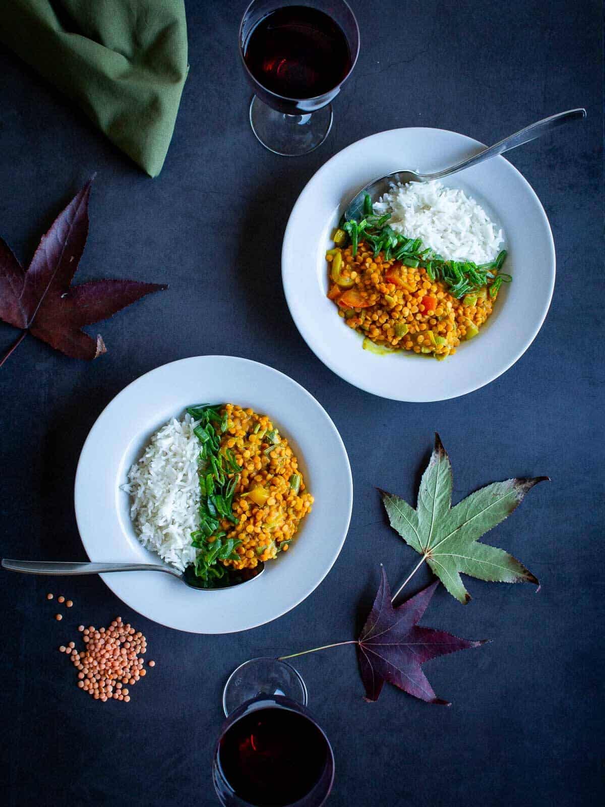 creamy red lentil curry plates served with basmati rice and a glass of wine.