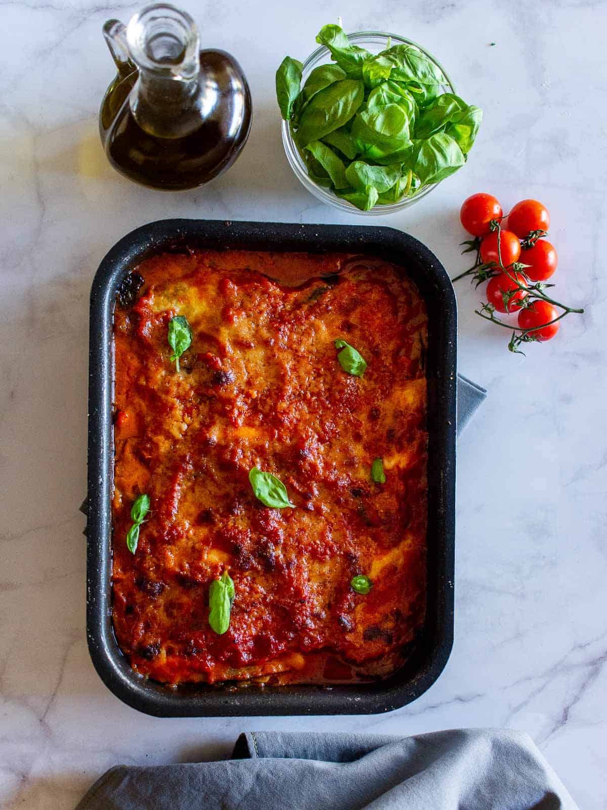 eggplant parmesan baking tray with basil leaves on top.