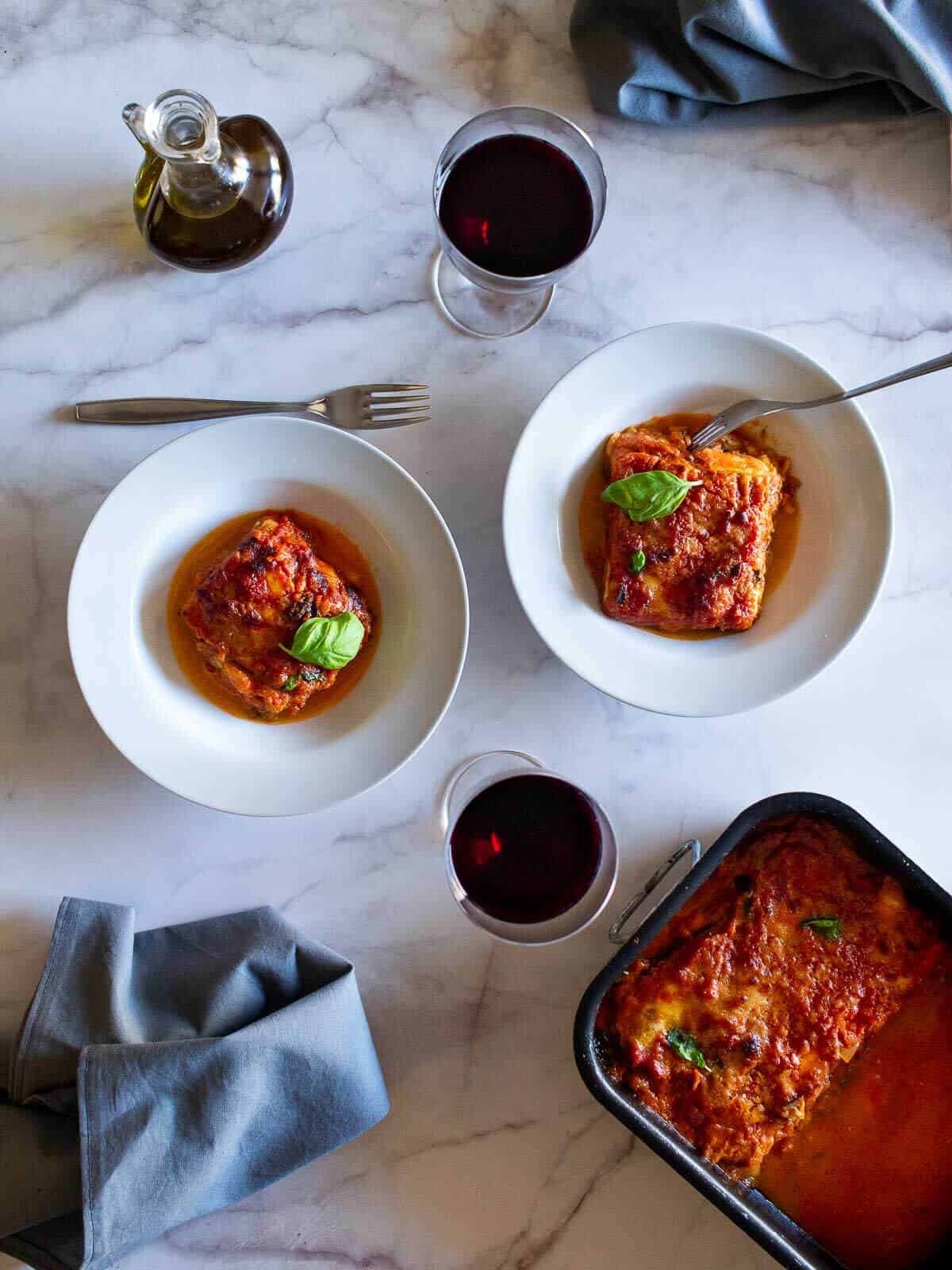 two plates of no-fry eggplant parmesan with red wine.