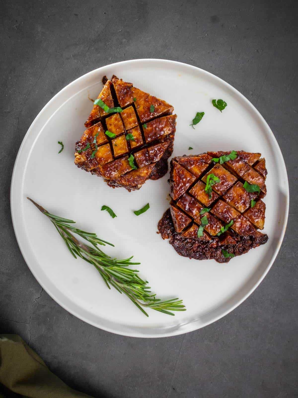 marinated baked tofu garnished with chopped parsley on a serving plate.