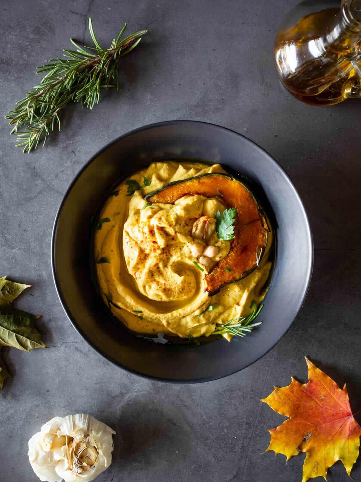 plated pumpkin hummus with a slice of roasted pumpkin on top as garnishing.