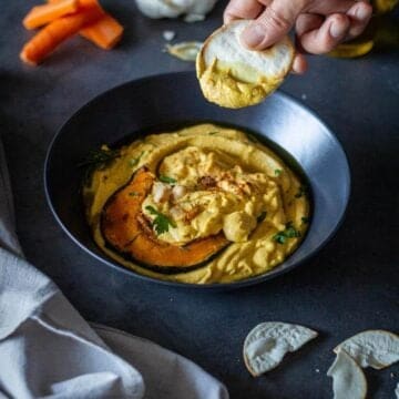 scooping pumpkin hummus with pita chips