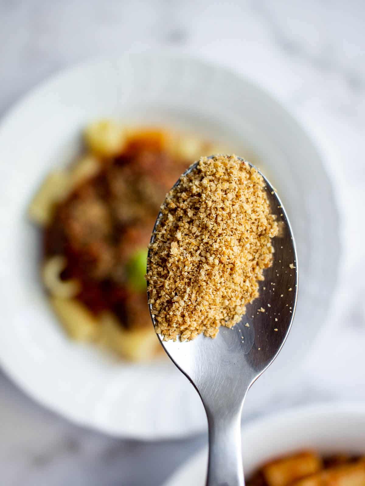 spoon with crumbly and textured vegan parmesan substitute.