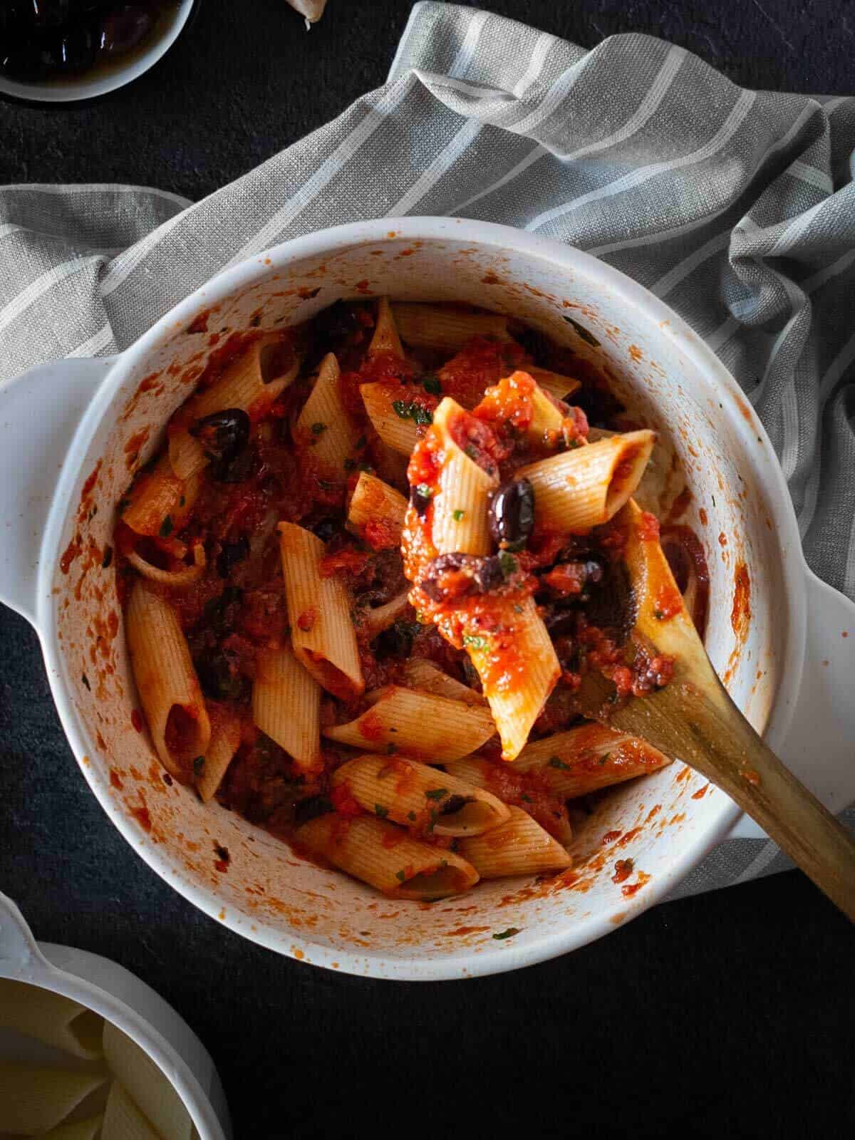 stir cooked pasta in puttanesca sauce