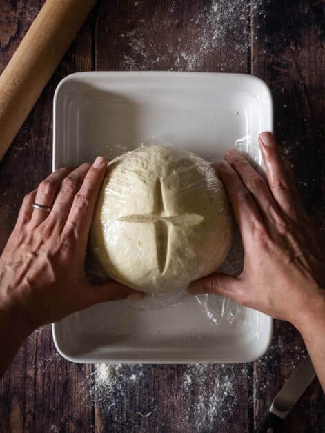 covering artisan bread dough with plastic wrap.
