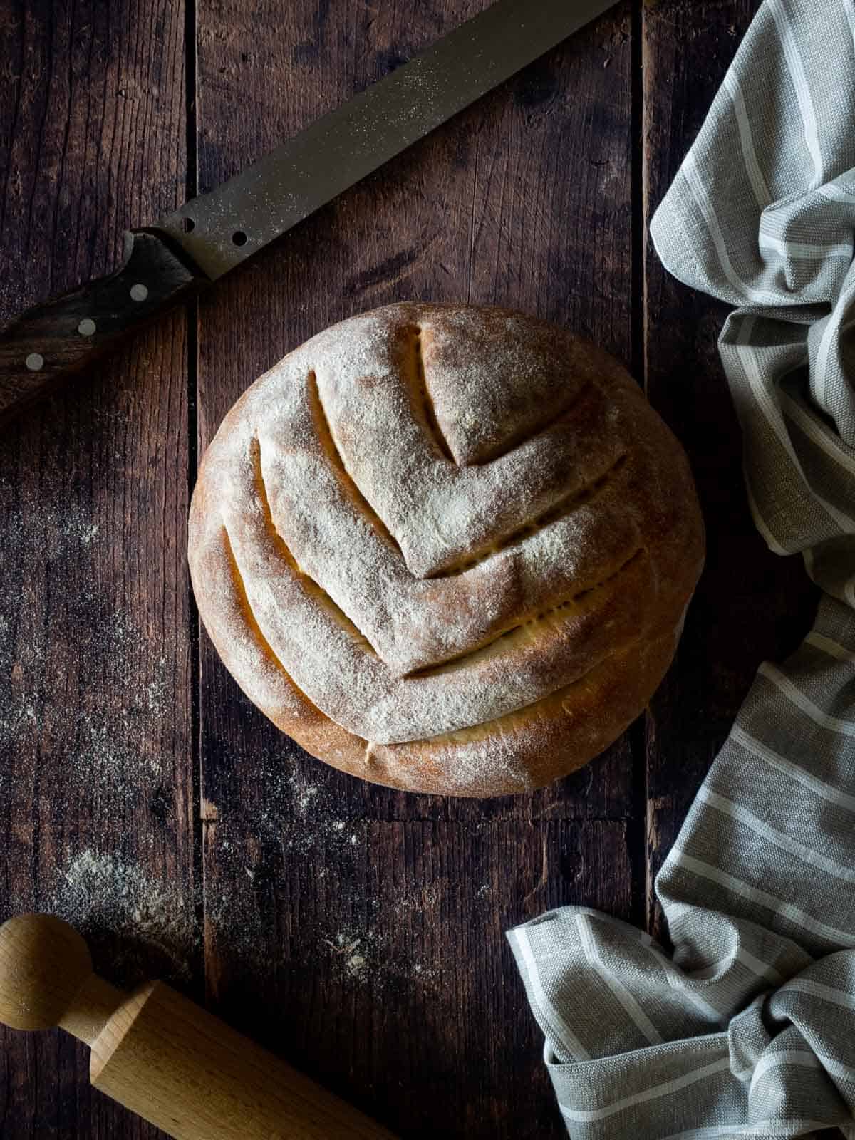 Italian artisan bread on table with a sewed knife.