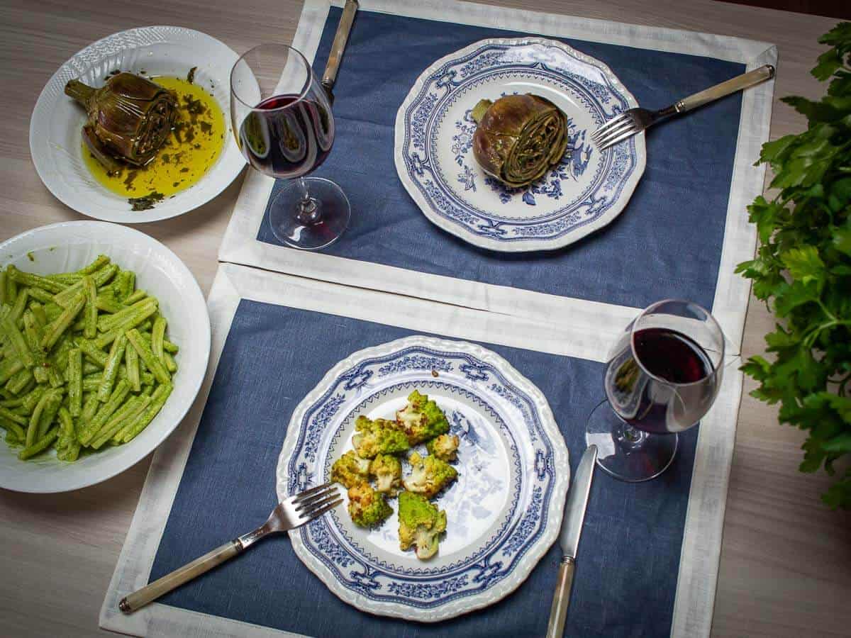 dinner table with Roma-Style artichokes, Romanesco Broccoli, and pasta made with a creamy vegan sauce.