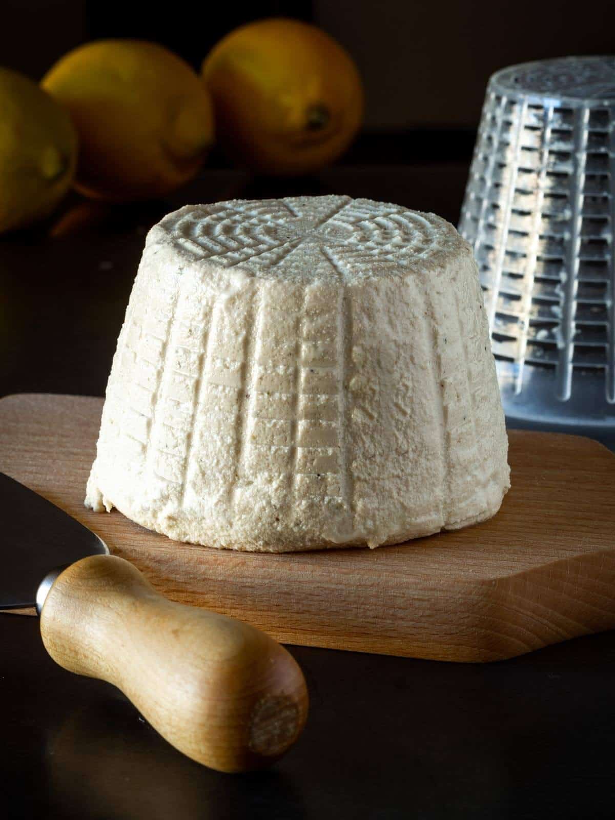 vegan ricotta on a serving wooden cheese table, shaped with a ricotta cheese press
