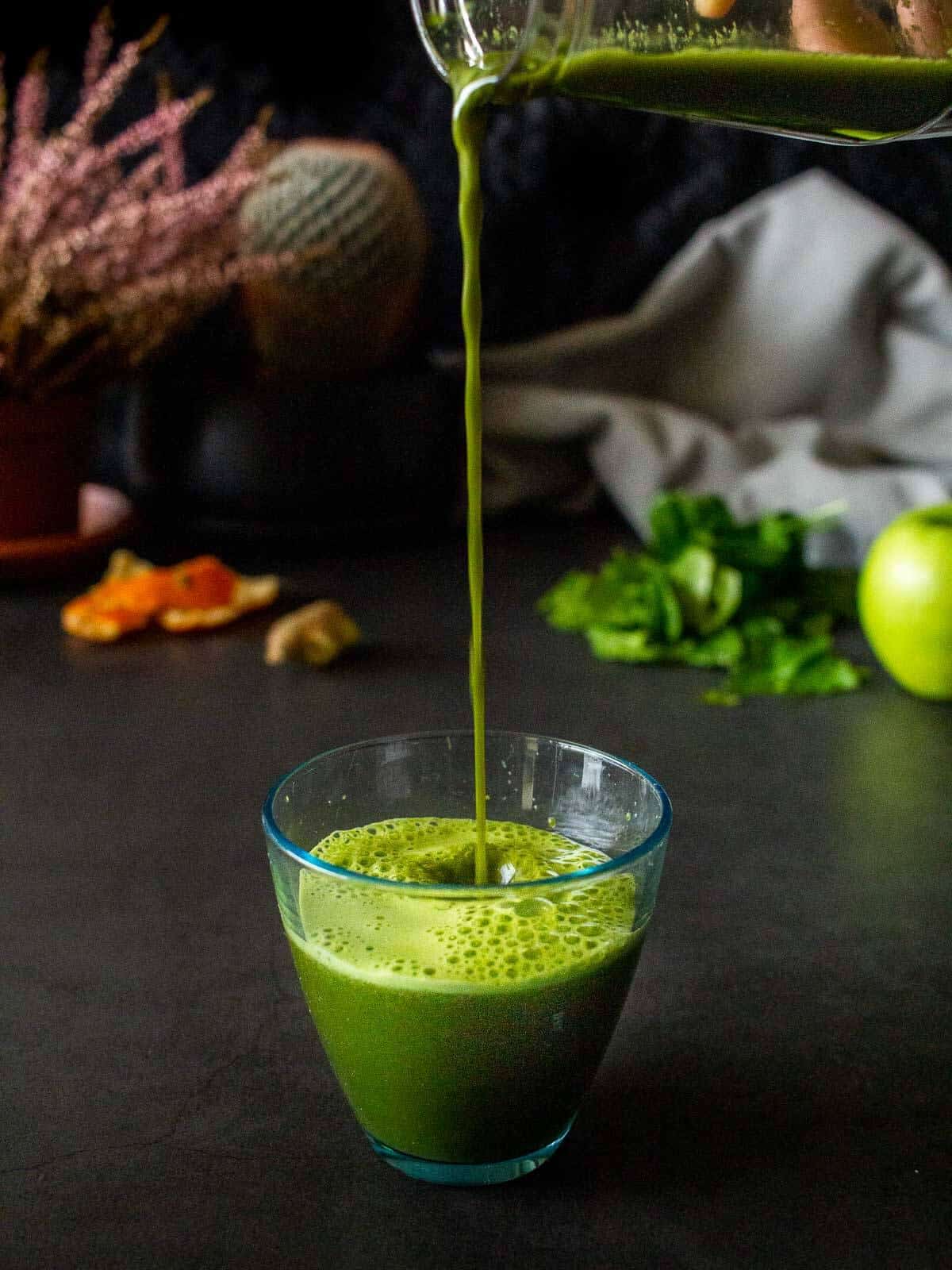 pouring kale and spinach juice from a bottle to a glass.