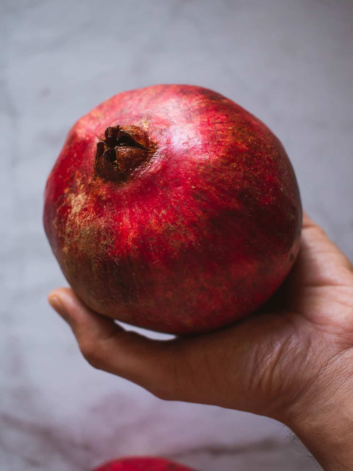 hand holding a whole pomegranate