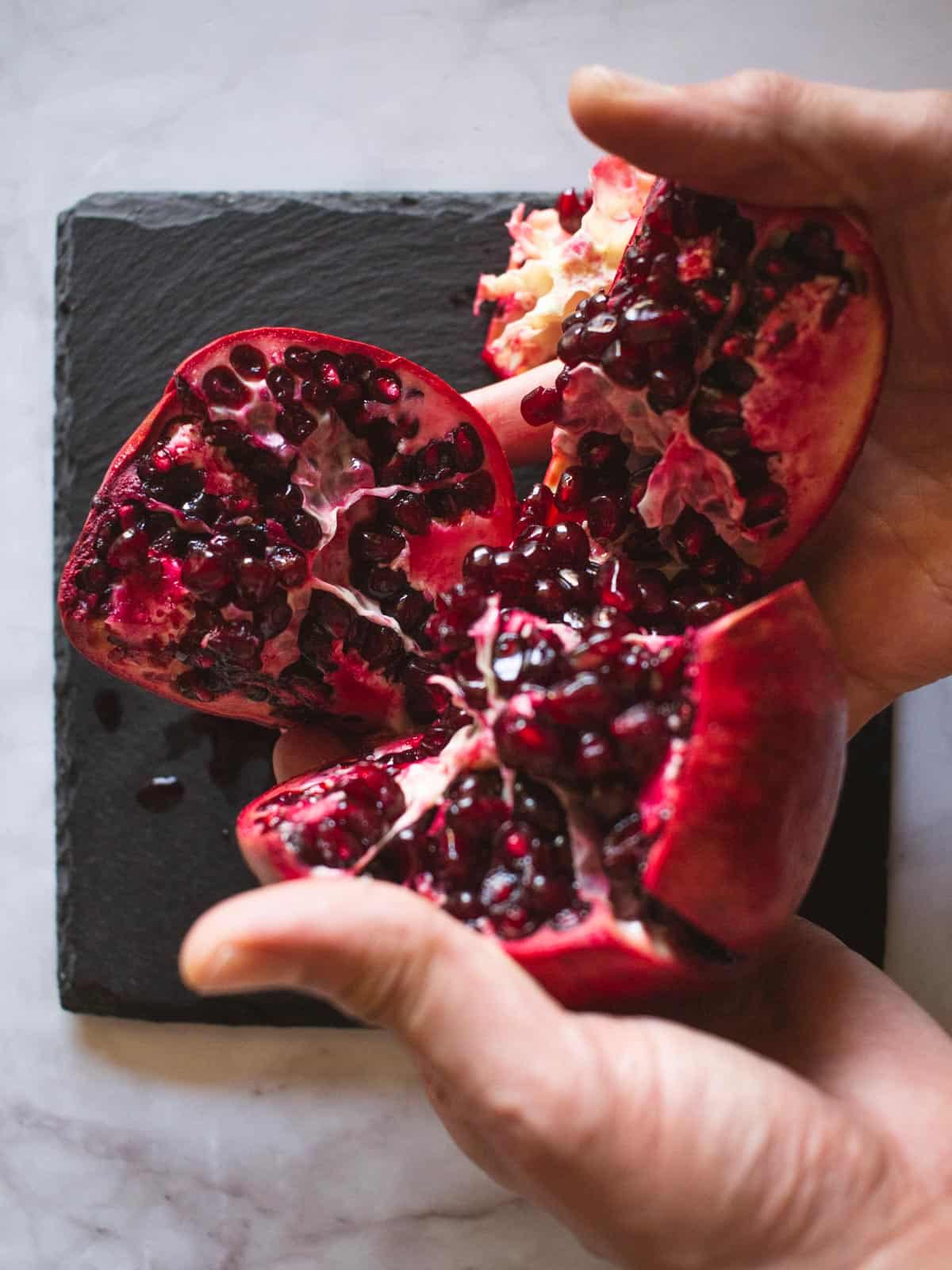 opening up the pomegranate fruit with hands