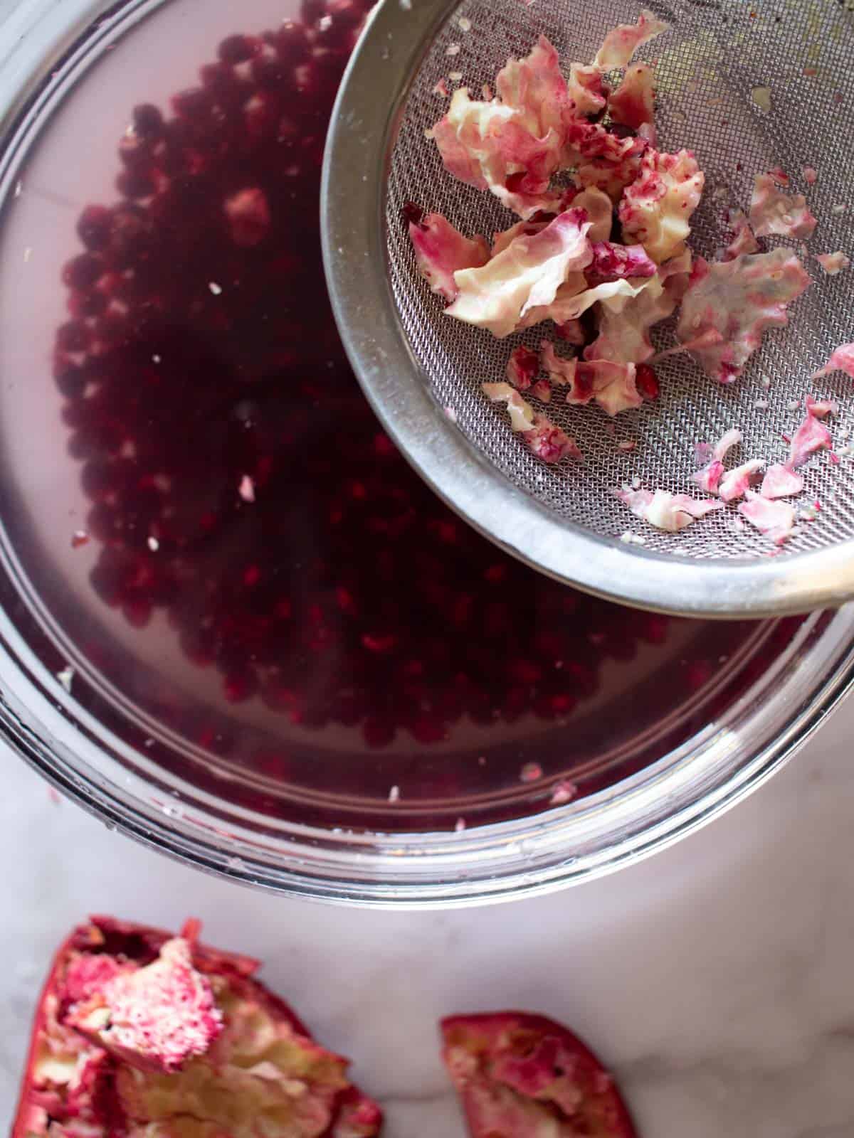 seeds in a bowl with water while straining and removing white membranes