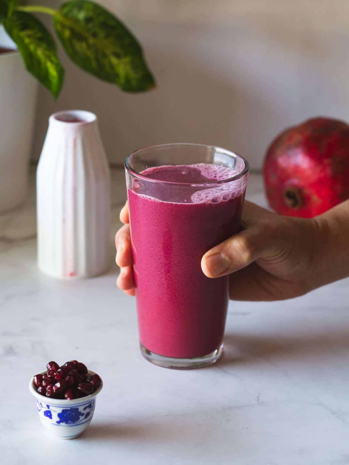 hand holding glass of pomegranate juice