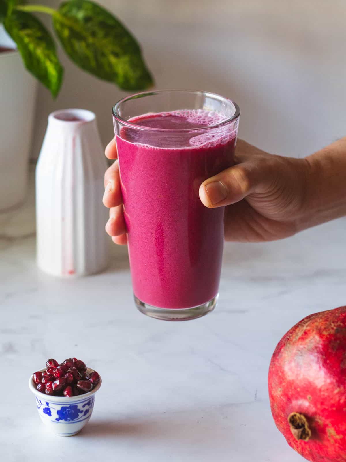 hand holding glass of pomegranate juice