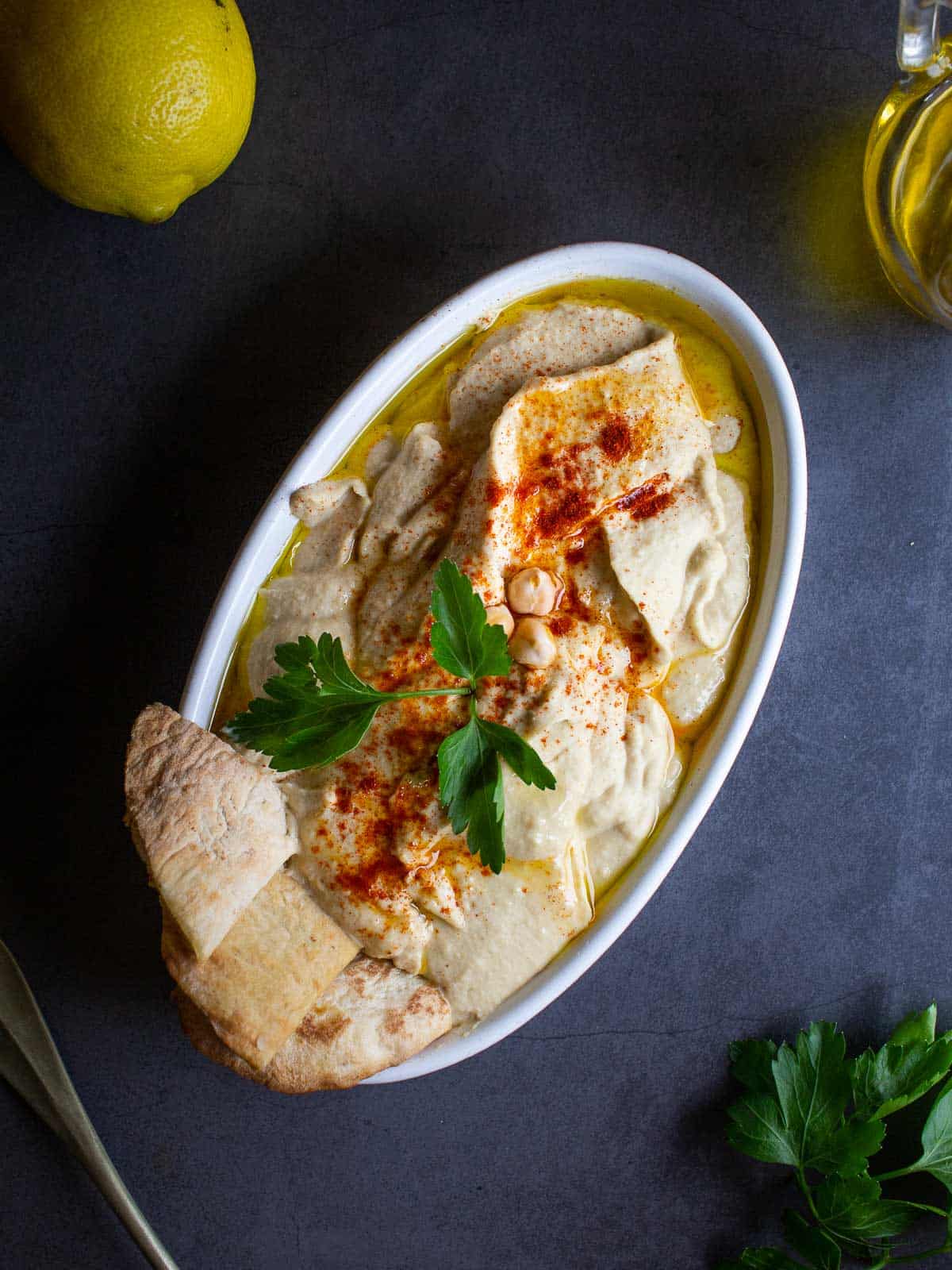 Hummus plated with pita bread and parsley.