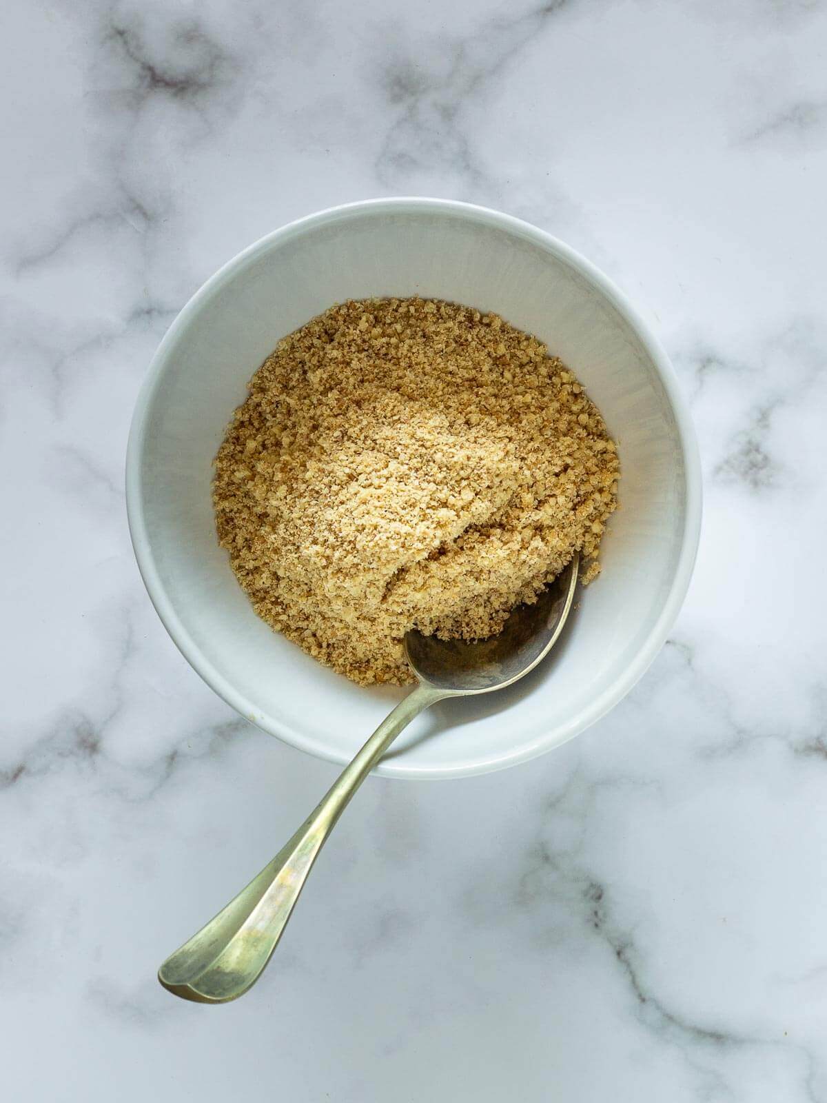 bowl with Vegan Parmesan Cheese and a scooping spoon.