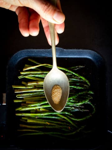 Adding Garlic Powder to the grilled asparagus.