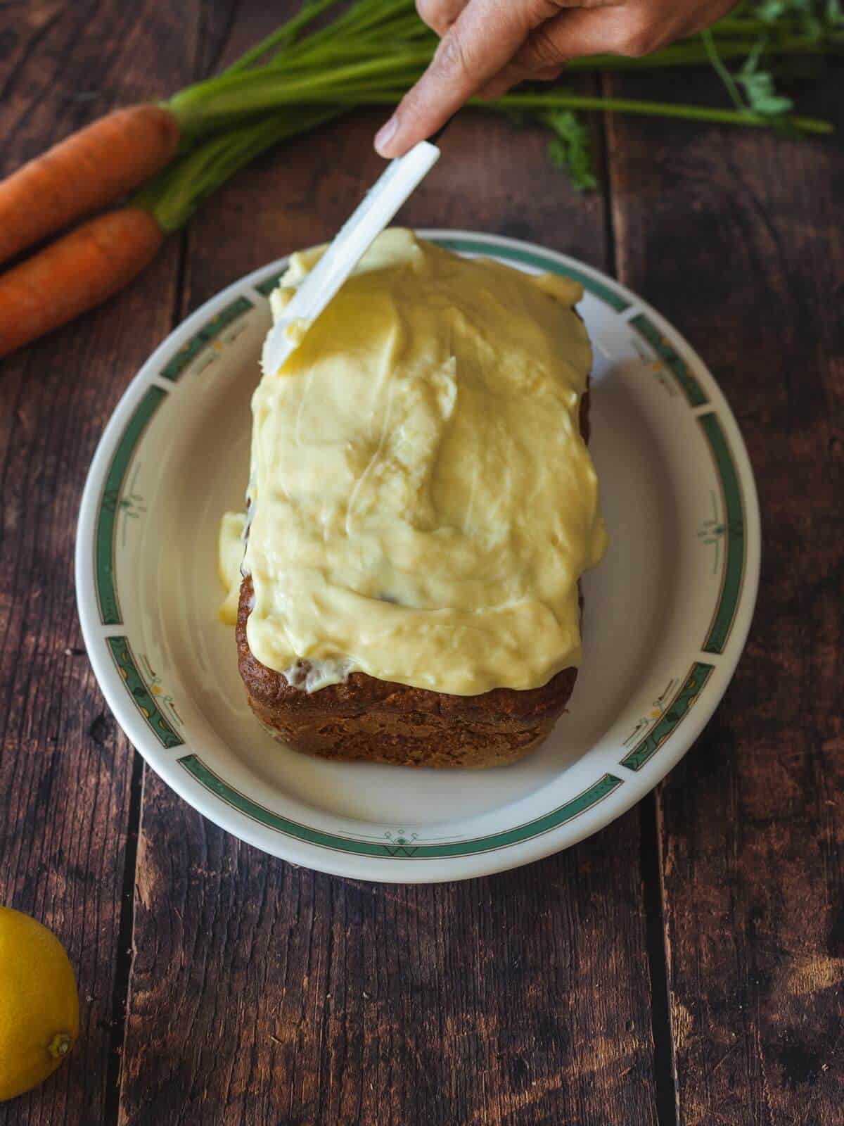 adding frosting on top of the carrot cake