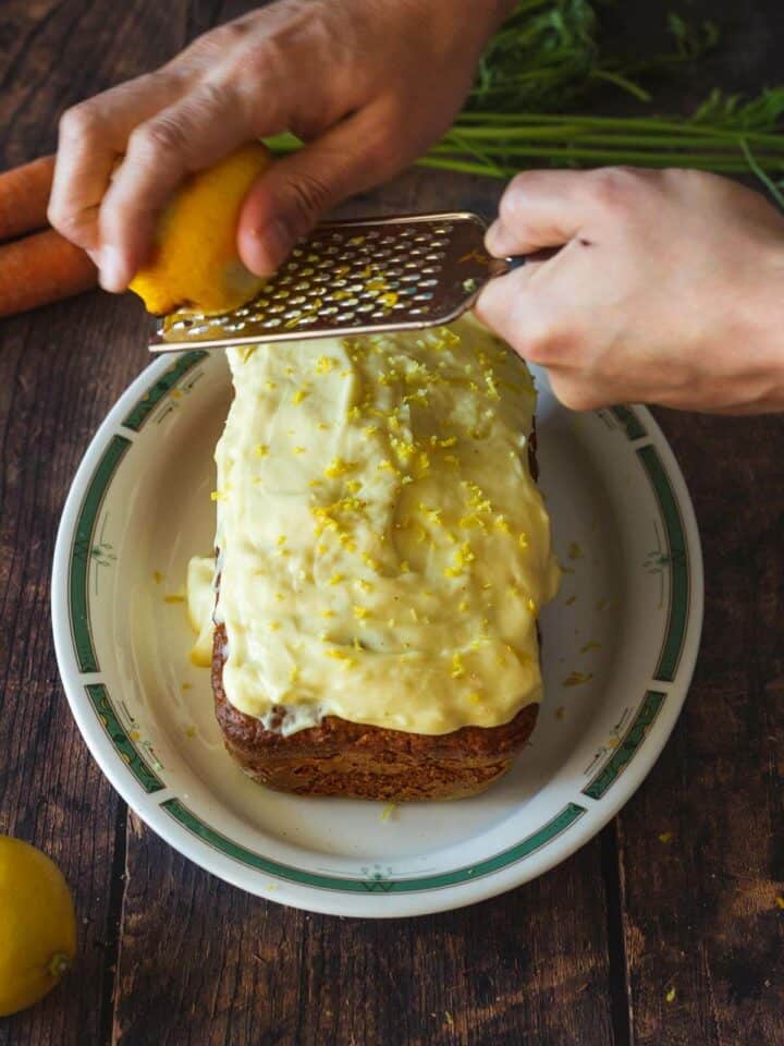 moist carrot loaf cake with frosting and lemon zest.