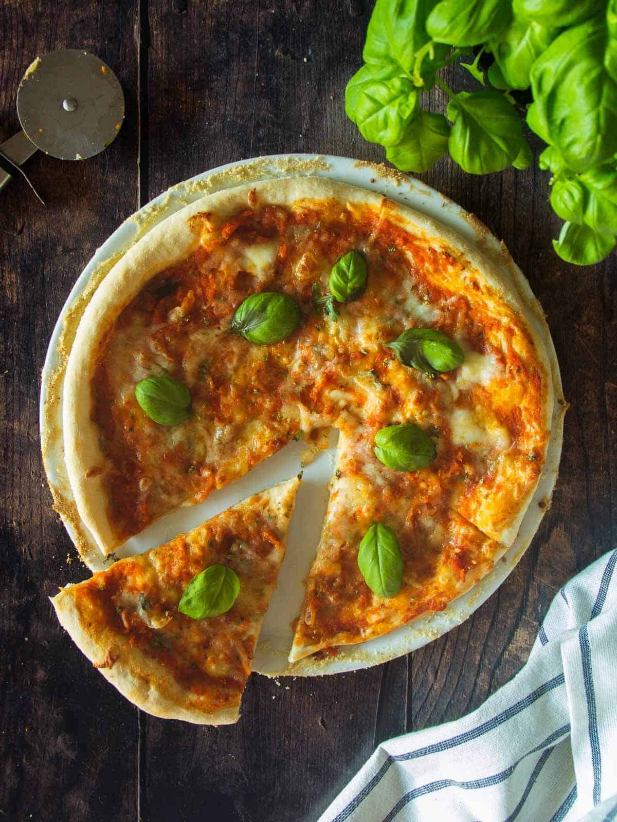 vegan cheese pizza made with our vegan pizza dough recipe and topped with fresh basil and vegan mozzarella.