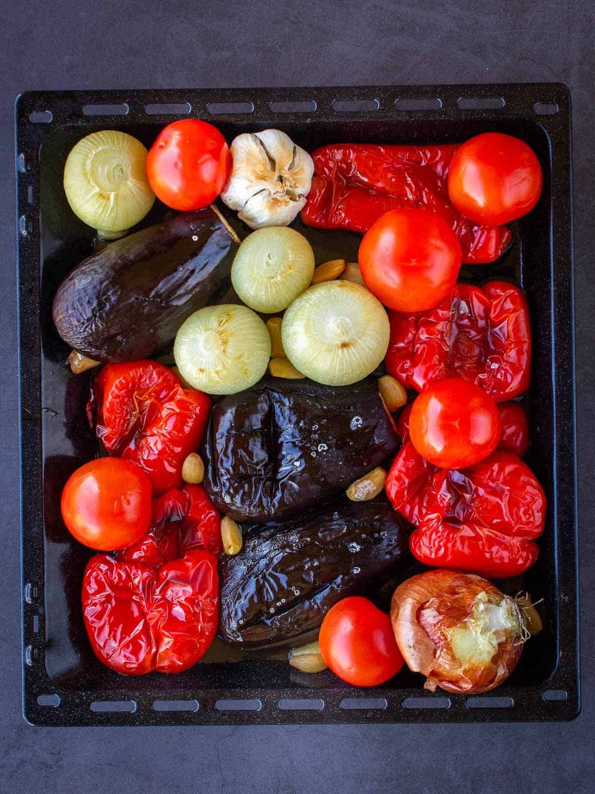 Roasted eggplants, red peppers, onions, and garlic cooked in baking sheet before adding whole tomatoes