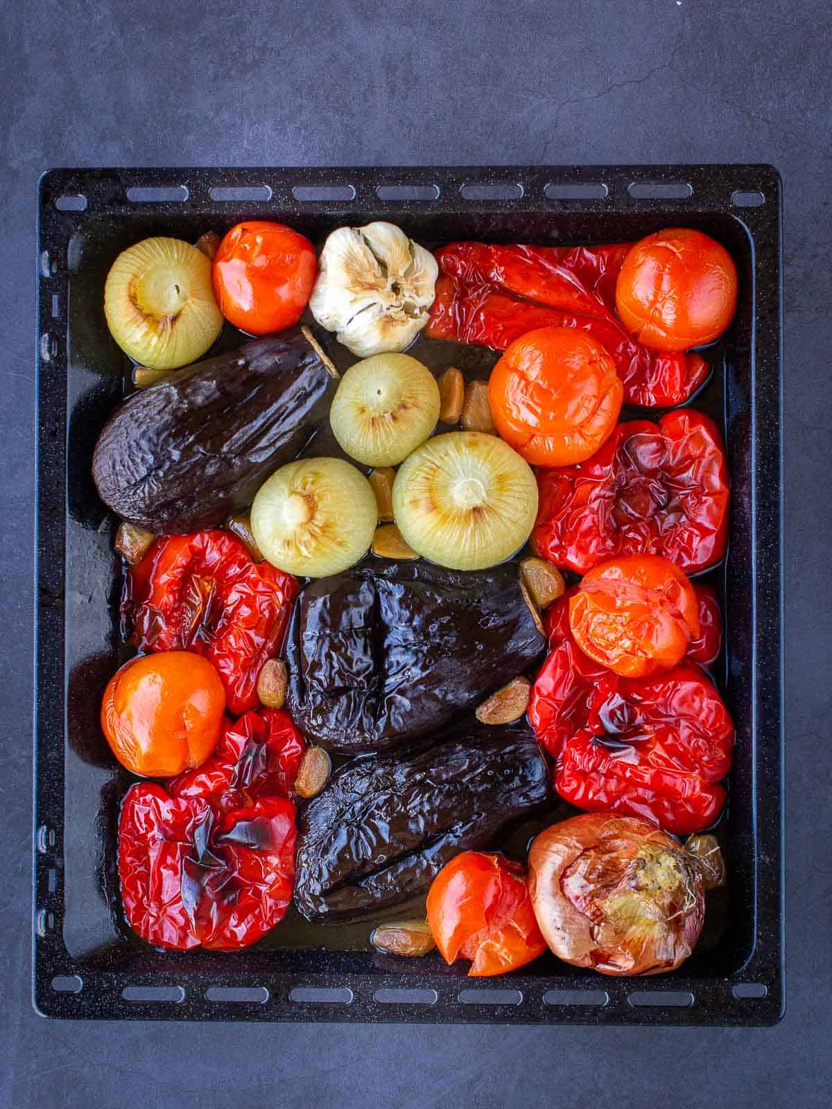 Roasted eggplants, red peppers, onions, and garlic cooked in baking sheet with whole tomatoes