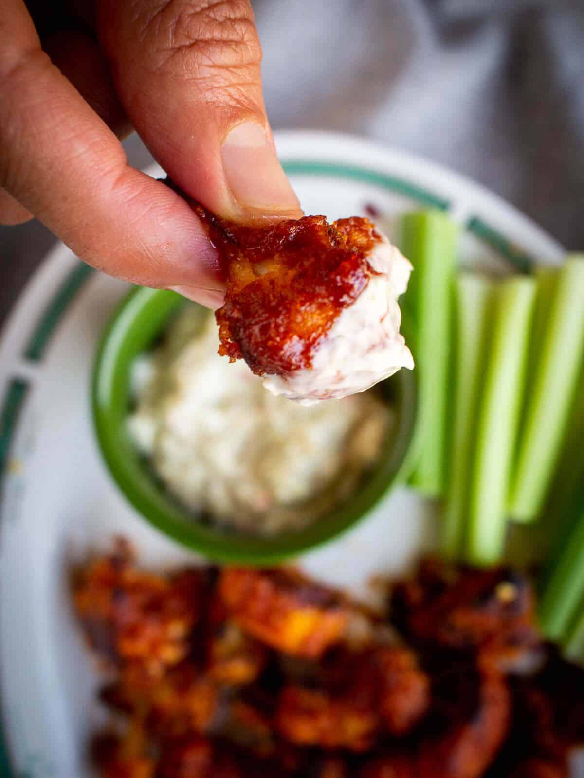 hand holding a dipped in ranch sauce vegan cauliflower wing.